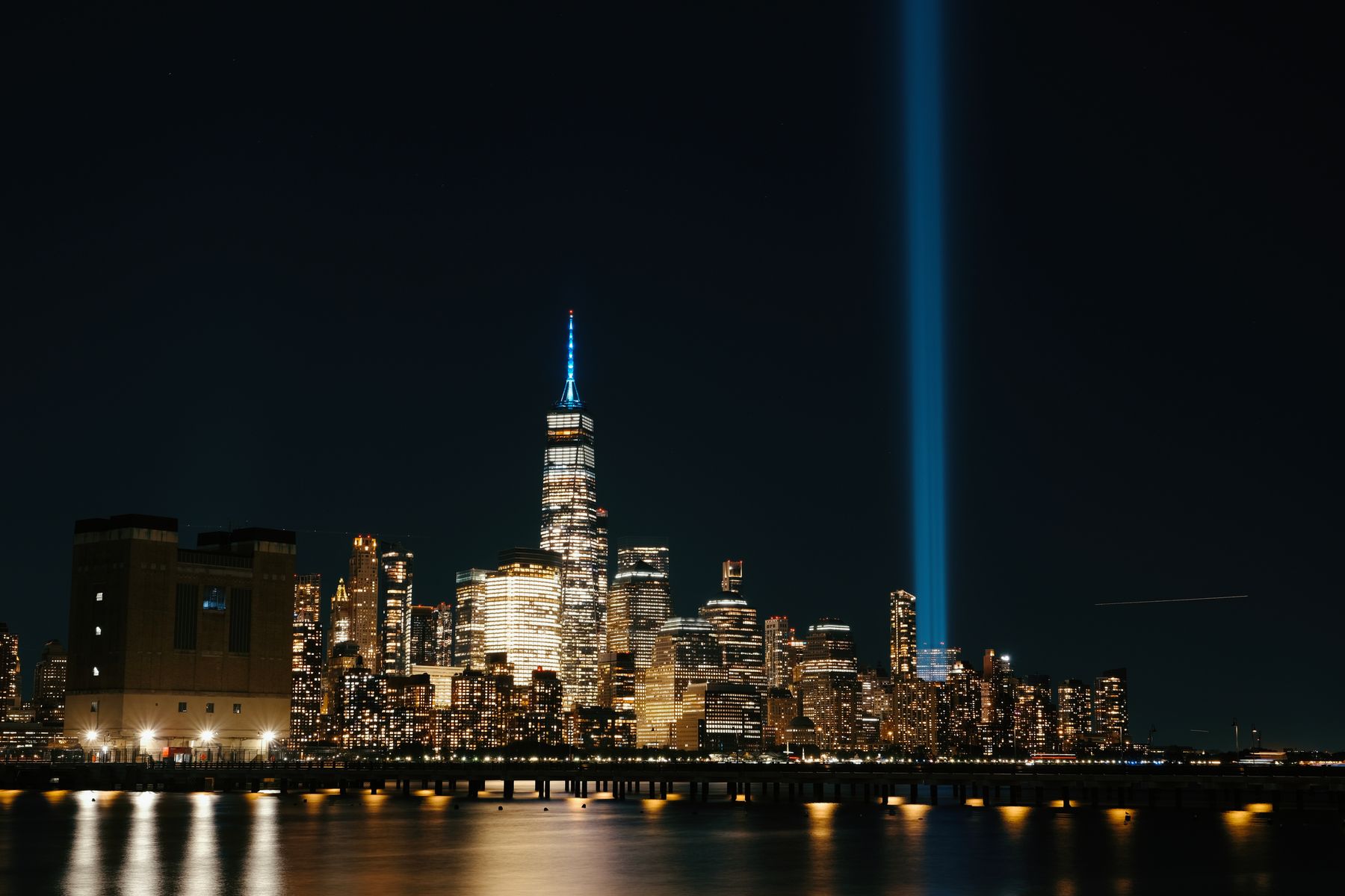 Tribute in Light beams rise above the illuminated New York City skyline at night