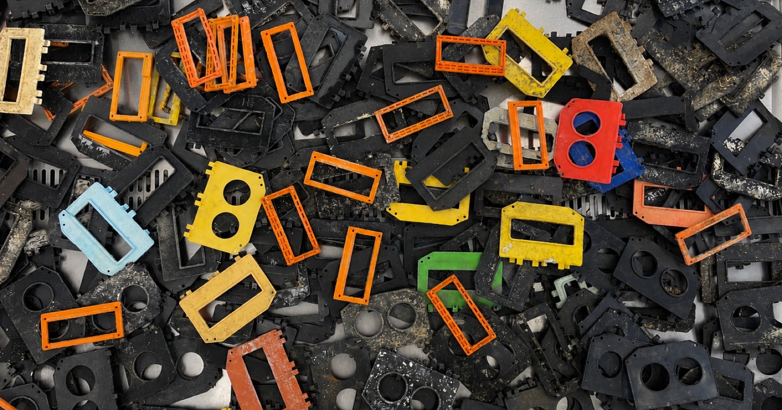 A pile of plastic lobster-trap escape vents in orange, yellow, red, blue and black, many encrusted with marine growth