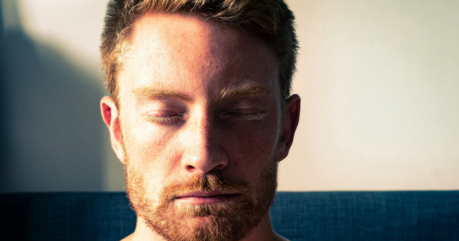 A man with his eyes closed in warm light